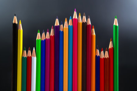 Colorful pencils in a dynamic wave formation, featuring shades of red, blue, yellow, and more, against a minimalist gray background. Ideal for art, education, and creativity topics.の写真素材