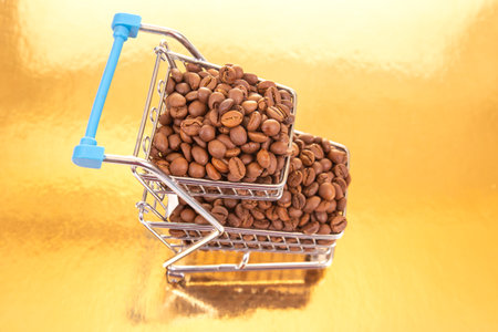Miniature shopping cart filled with roasted coffee beans on a golden background, symbolizing luxury and commerce. Perfect for coffee brands, market themes, or upscale product promotions.の写真素材