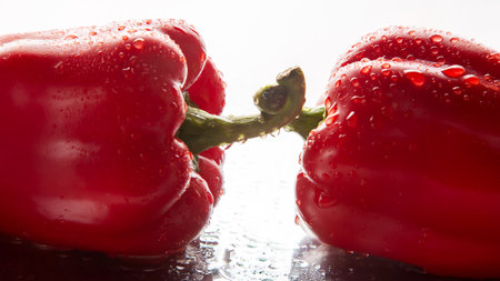 two red peppers in the water droplets on white background.