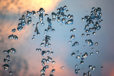 flying drops of water fountain close-up on the background of the skyの写真素材