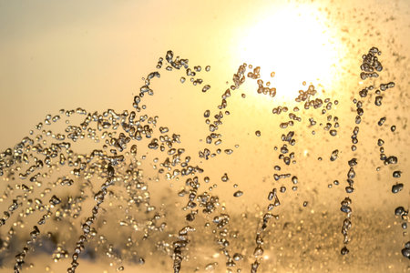 silhouettes of drops falling water fountain against the backdrop of the setting sunの写真素材