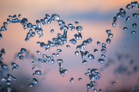 flying drops of water fountain close-up on the background of the skyの写真素材