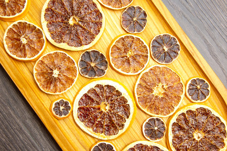 dried citrus fruit pieces are laid out on a wooden board for product transfer. vitamin foodの写真素材