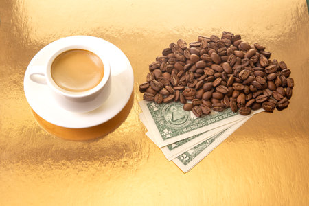 a white ceramic cup filled with rich Turkish coffee, surrounded by roasted coffee beans and US one-dollar bills on a golden surface, symbolizing the value and luxury of coffee.の写真素材
