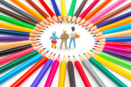 Colorful pencils form a circular frame around three tiny figurines, showcasing a playful and creative concept against a clean white background.の写真素材