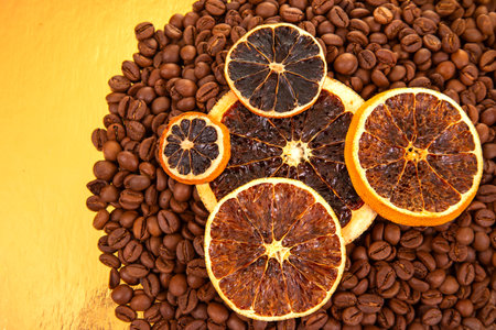 Close-up of coffee beans with dried orange slices on a golden backdrop, highlighting natural textures in food photography. coffee aroma and taste citrus descriptorsの写真素材