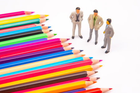 Brightly colored pencils fanned out on a white backdrop, paired with three miniature business figures, blending art and professional themes. miniature peopleの写真素材
