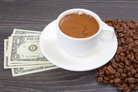 Enjoying a rich cup of coffee with fresh beans and a touch of cash on a wooden table. coffee businessの写真素材