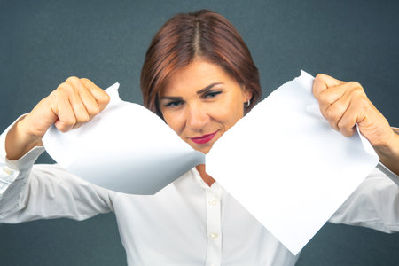 Beautiful business woman tearing white paper in halfの写真素材