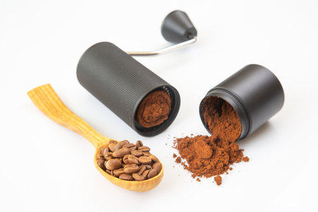 disassembled coffee grinder showing ground coffee inside, with a spill of coffee powder on a white background, perfect for commercial use.の写真素材