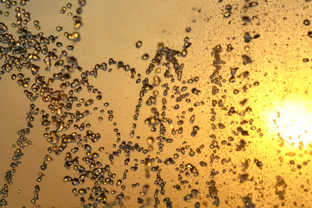 silhouettes of drops falling water fountain against the backdrop of the setting sunの写真素材
