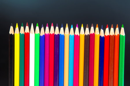Colorful pencils in a dynamic wave formation, featuring shades of red, blue, yellow, and more, against a minimalist gray background. Ideal for art, education, and creativity topics.の写真素材