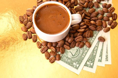 striking image of a Turkish coffee cup with coffee beans and US one-dollar bills on a golden background, representing luxury and tradeの写真素材