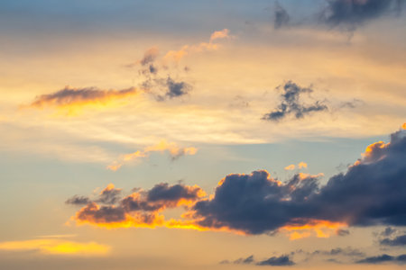 Vibrant sunset over the horizon with a colorful sky of orange, pink, and blue hues. Scattered clouds reflect the sunlight, creating a serene and picturesque scene, perfect for nature, travelの写真素材