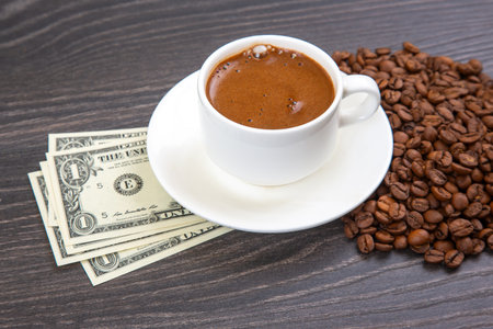 Enjoying a rich cup of coffee with fresh beans and a touch of cash on a wooden table. coffee businessの写真素材