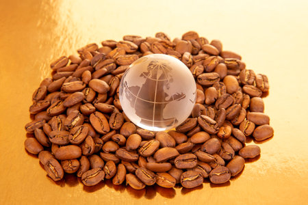 Roasted coffee beans with a glass globe showing the world map, symbolizing global coffee trade, on a warm background. Perfect for coffee culture and international themes.の写真素材