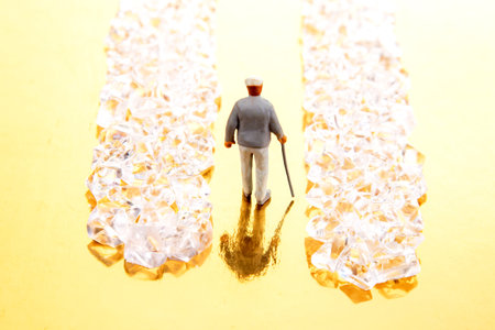 A tiny suited figure walks through a sparkling crystal pathway on a reflective golden base, embodying the pursuit of success and luxury.の写真素材