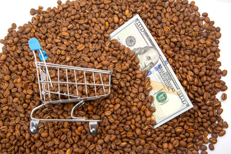 Coffee trade and economy depicted with a mini shopping cart, roasted coffee beans, and US banknotes, reflecting global market fluctuations.の写真素材