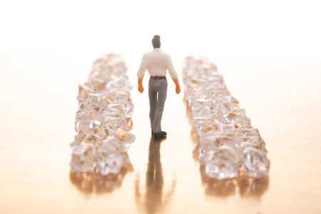 A small businessman walks between gleaming crystal piles on a reflective golden floor, representing...