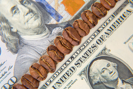 Roasted coffee beans placed on a US dollar bill, with visible Federal Reserve text and a portrait,...