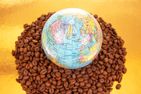 Roasted coffee beans supporting a detailed world globe on a golden backdrop, highlighting global coffee production. Perfect for food and trade photography.の写真素材