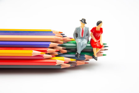 Colorful pencils spread across a white surface, with miniature businessmen standing, merging artistic expression with corporate imagery. miniature peopleの写真素材
