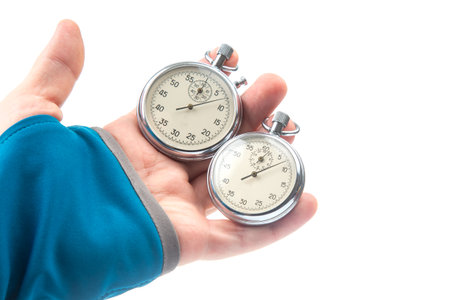 Two mechanical stopwatches hang on the fingers of a male hand. Time part precision. Measurement of...