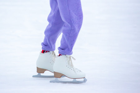 Bright winter afternoon at an ice rink where a young skater glides gracefully across the surface in...