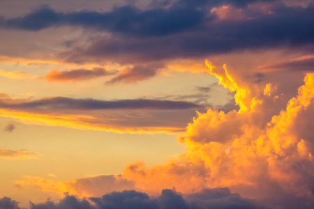 Beautiful clouds painted in shades of orange, pink, and purple stretch across the sky during sunset. The fading light creates a serene atmosphere, inviting calm and reflection at day's end.の写真素材