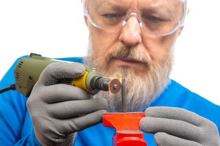 A craftsman focuses intently while using a rotary tool to grind and shape metal. Wearing safety...