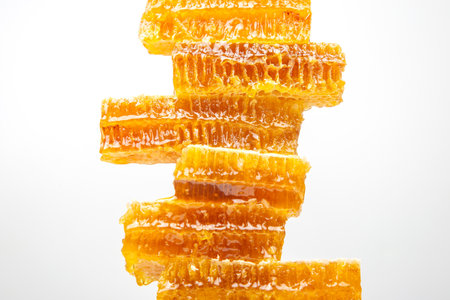 Glorious pieces of honeycomb are stacked in a vertical arrangement, shimmering with golden honey.の写真素材