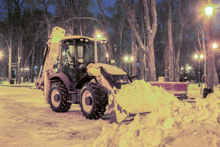 A snow removal machine works tirelessly to clear layers of fresh snow in a tranquil park....