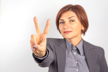 A confident businesswoman presents a peace sign with her right hand.の写真素材