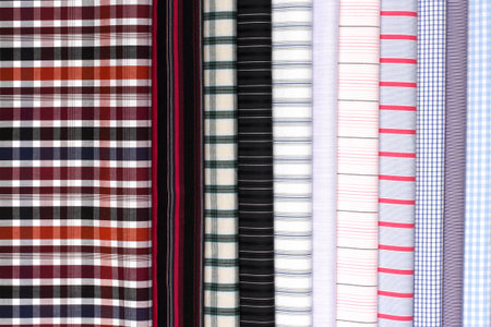 Colorful plaid and striped fabrics are neatly arranged in a bright, well-lit area, showing a variety of patterns and colors.の写真素材