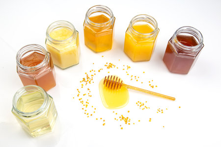 Different jars containing various types of honey are arranged artistically, showing their rich colors.の写真素材