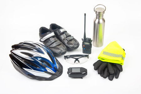 Essential cycling accessories like a helmet, shoes, communication device, and visibility gear are showcased against a plain background, highlighting their importance.の写真素材