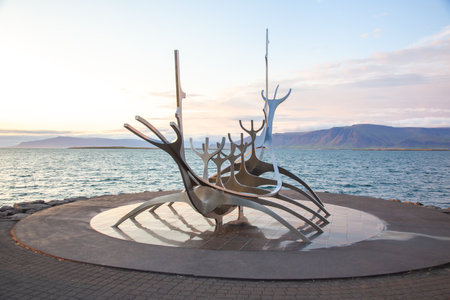 Visitors admire the Sun Voyager sculpture by the waterfront in Reykjavik as the sun sets over the ocean.の写真素材