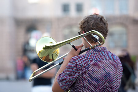 Reflection of the street in the instrument. male musician plays the trombone. music and creativity. jazz and bluesの写真素材