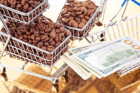 A shiny gold background hosts a cart of coffee beans and $100 bills, merging ideas of luxury, money, and the profitable coffee trade.の写真素材