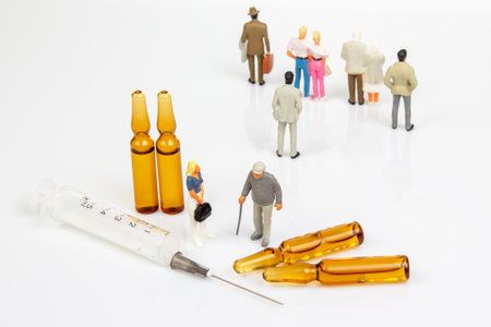 Miniature doctor and elderly figurine stand near three amber vials, a syringe, and a broken vial on a white surface, symbolizing healthcare, vaccination, or medical care concerns.の写真素材