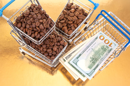 A stack of $100 bills lies beneath a cart of coffee beans on a golden backdrop, illustrating the lucrative coffee market and financial gainの写真素材