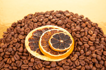 Warm coffee beans and dried orange slices on a reflective golden surface, creating a gourmet aesthetic for food styling. coffee aroma and taste citrus descriptorsの写真素材