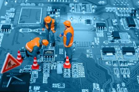 Miniature engineers fixing error on chip of circuit board. Computer repair concept. Close-up view.の写真素材