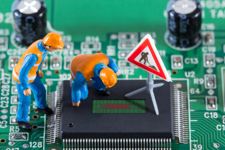 Miniature engineers looking at code on chip of circuit board. Computer repair concept. Close-up view.の写真素材