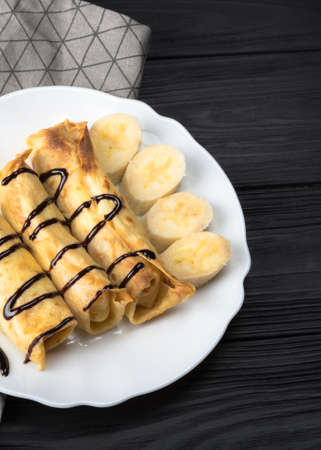 Pancakes with cottage cheese and a banana with chocolate syrup.の写真素材