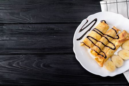 Pancakes with cottage cheese and a banana with chocolate syrup.の写真素材