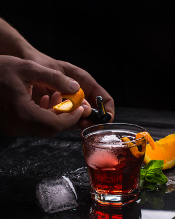 Mezcal Negroni cocktail with fire, orange peel and hands. Italianの写真素材