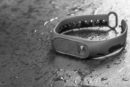 wet fitness bracelet, fitness tracker on a black slate background with drops of waterの写真素材
