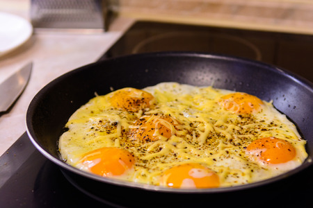 Fried eggs in the frying pan with cheese at home. Homemade.の写真素材