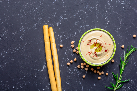 Healthy food. Vegetable sources of protein. Bowl of hummus, on black stone table, chickpeas. Copy space.の写真素材